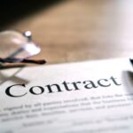 Contract sheet with glasses and a pen on a wooden background